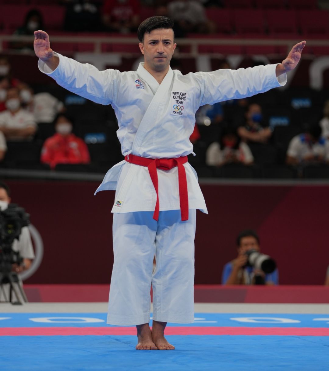Αθλητής kata σε στάση ετοιμότητας με λευκό karate gi και κόκκινη ζώνη
